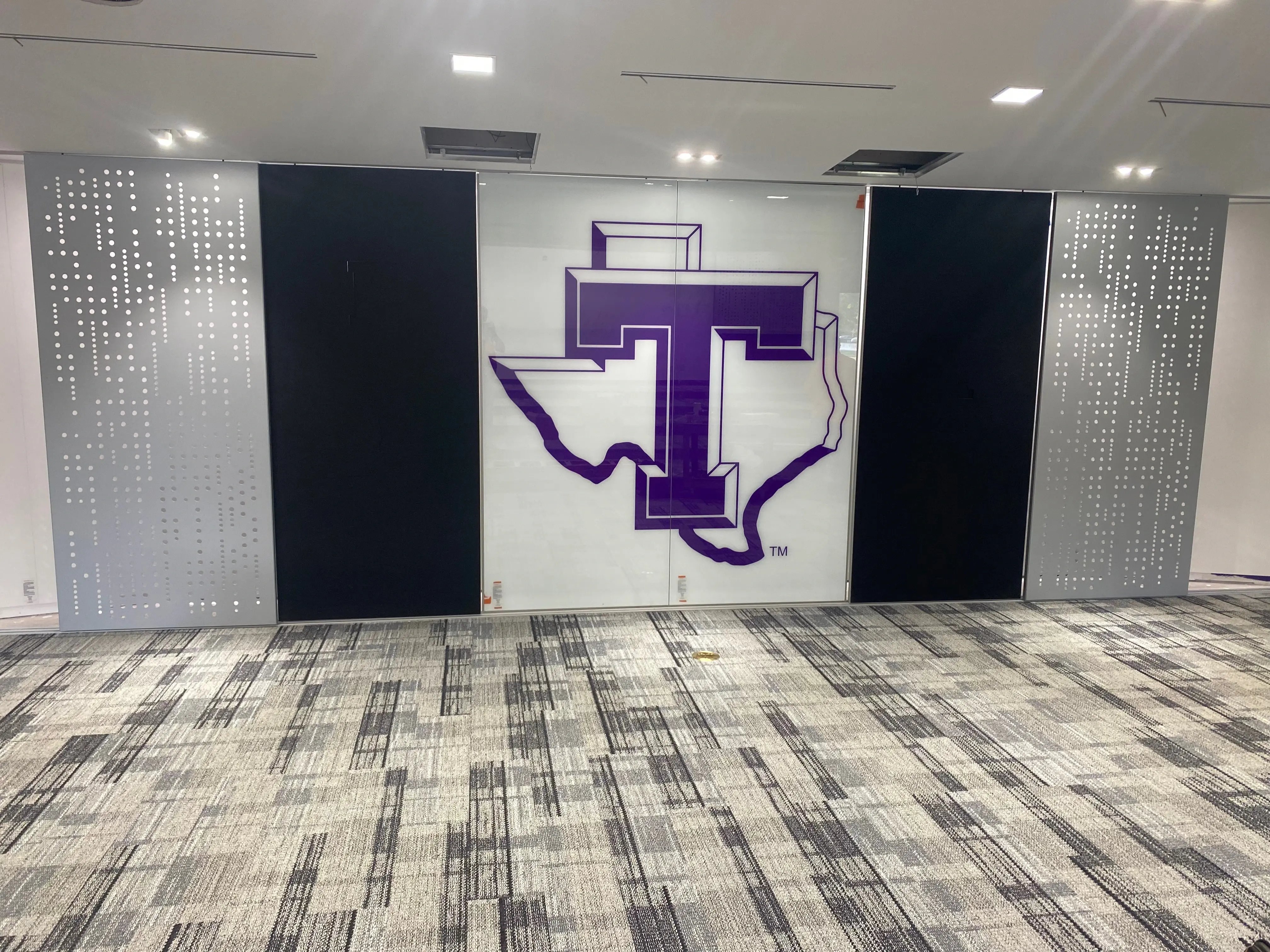 INTERSECTION SLIDE PERFORATED ALU PANELS CUT-OUT ACOUSTICOR PANELS AND GRAPHIC LOGO GLASS PANELS